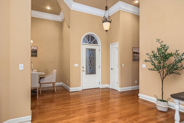 entrance foyer featuring recessed lighting, a high ceiling, wood finished floors, baseboards, and crown molding