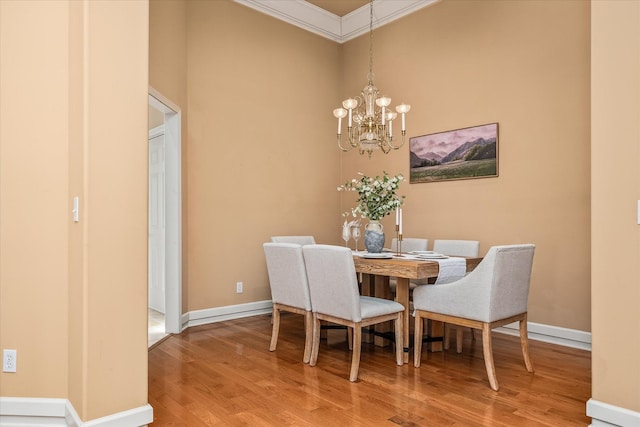 dining area with ornamental molding, a notable chandelier, baseboards, and wood finished floors