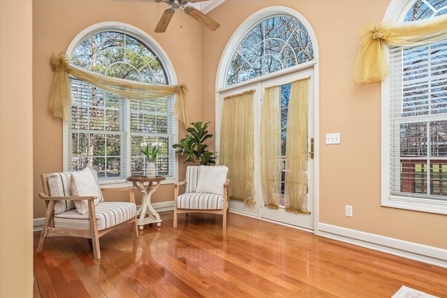 living area with wood finished floors, a ceiling fan, and baseboards