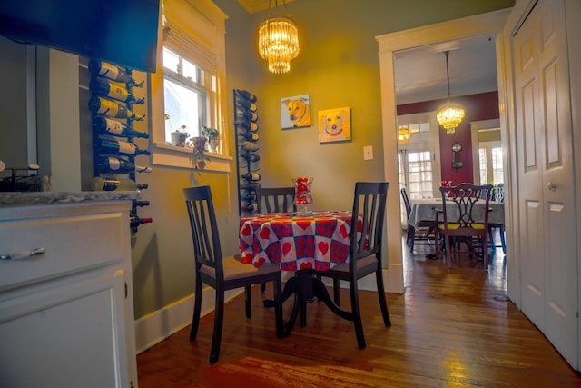 dining space featuring a healthy amount of sunlight, dark wood finished floors, and an inviting chandelier