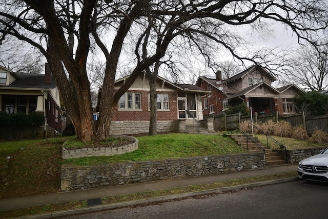 craftsman-style home featuring brick siding, fence, and stairs