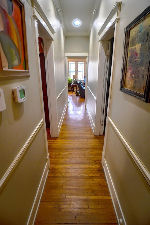 corridor with baseboards, wood finished floors, and crown molding