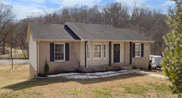 single story home with roof with shingles, a front lawn, and brick siding