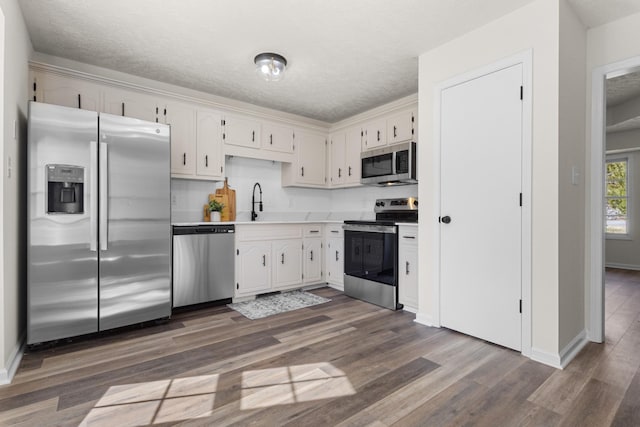 kitchen featuring appliances with stainless steel finishes, white cabinets, light countertops, and dark wood-type flooring