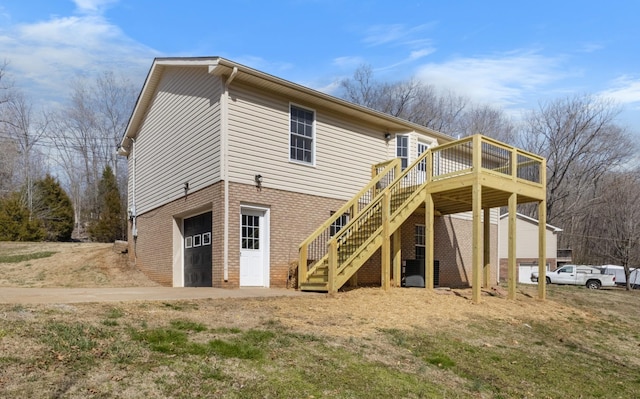 back of property featuring a garage, brick siding, stairway, and a wooden deck