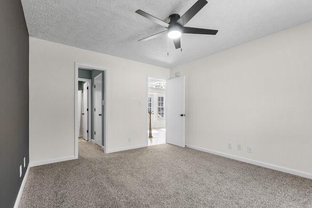 unfurnished bedroom with light carpet, a textured ceiling, a ceiling fan, and baseboards