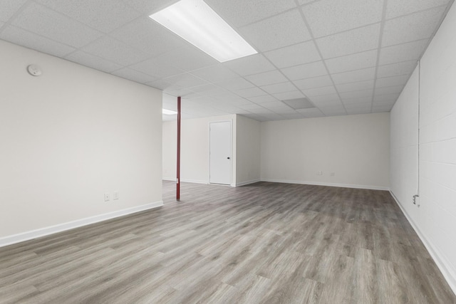 finished basement with light wood-type flooring, baseboards, and a paneled ceiling