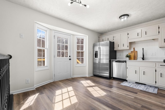 kitchen featuring white cabinets, appliances with stainless steel finishes, dark wood-style flooring, light countertops, and a sink