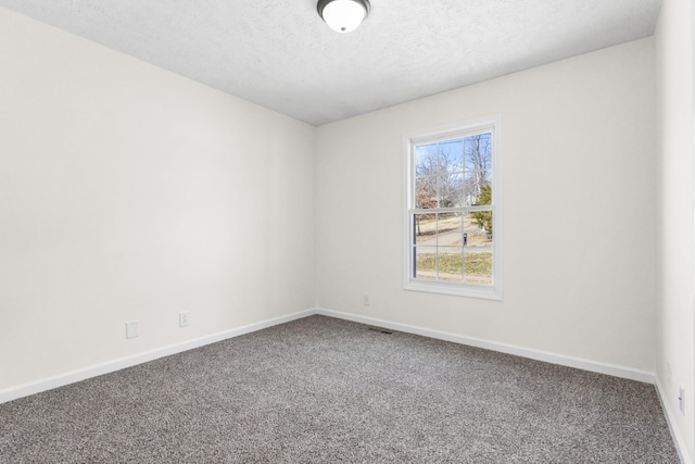 spare room with carpet, a textured ceiling, and baseboards