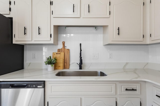 kitchen with light stone counters, backsplash, white cabinetry, a sink, and dishwasher