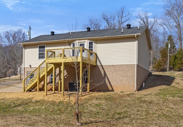 rear view of property with brick siding, a lawn, a wooden deck, and stairs