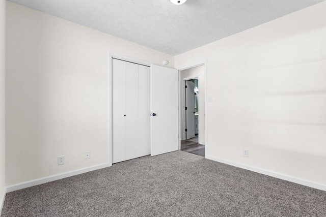 unfurnished bedroom featuring a textured ceiling, carpet floors, a closet, and baseboards