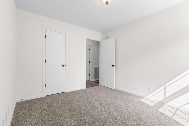 unfurnished bedroom with carpet flooring, visible vents, and baseboards