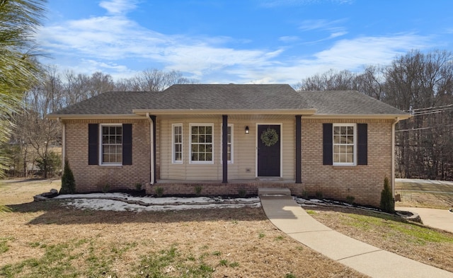 ranch-style house featuring brick siding, a front lawn, and a shingled roof