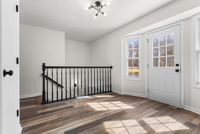 interior space with a notable chandelier, wood finished floors, and baseboards