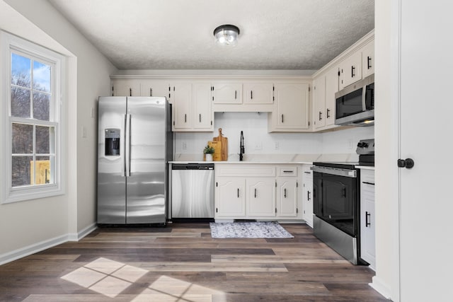 kitchen with stainless steel appliances, white cabinets, light countertops, and a sink