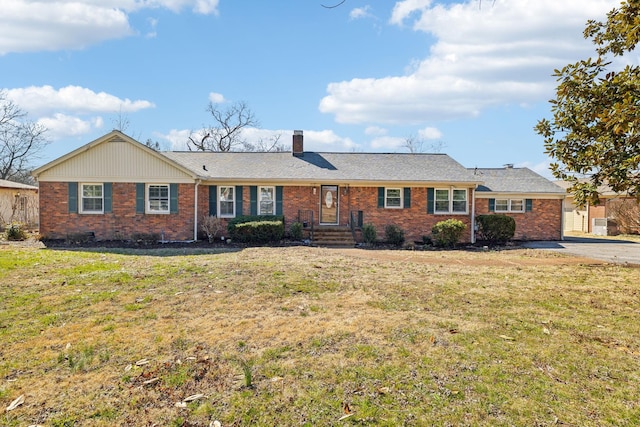 single story home featuring a chimney, a front lawn, and brick siding