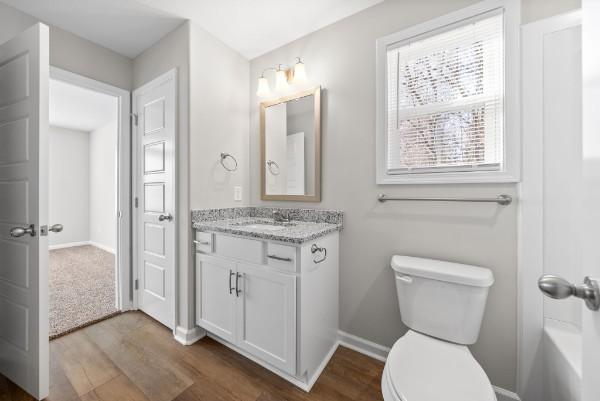 bathroom with baseboards, vanity, toilet, and wood finished floors