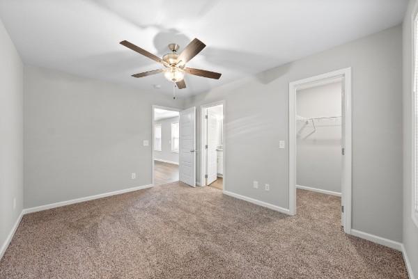 unfurnished bedroom with a closet, light carpet, a spacious closet, and baseboards