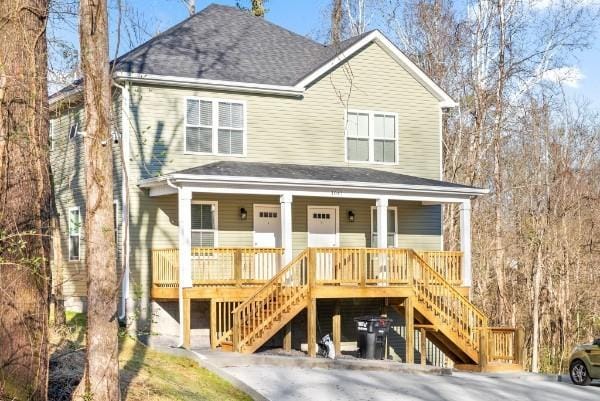 view of front of home with roof with shingles, a porch, and stairway