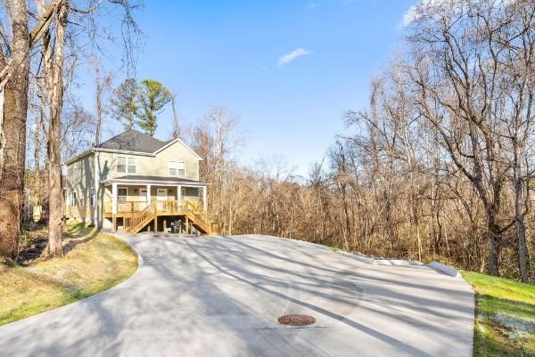 view of front of property with driveway, covered porch, and stairway