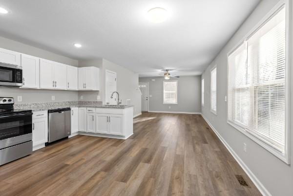 kitchen featuring light countertops, appliances with stainless steel finishes, open floor plan, white cabinets, and a sink