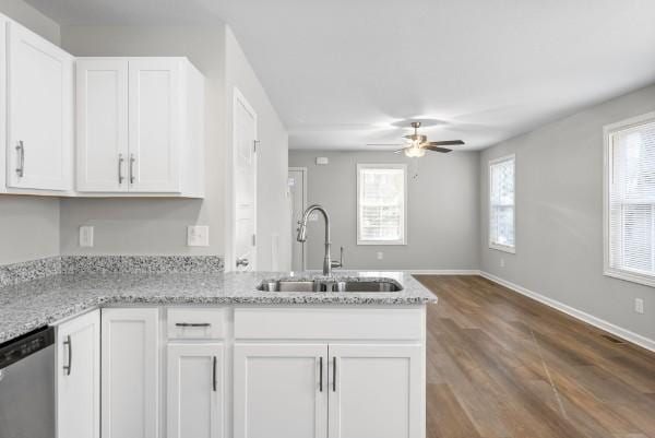 kitchen featuring light stone counters, white cabinets, a sink, and dishwasher