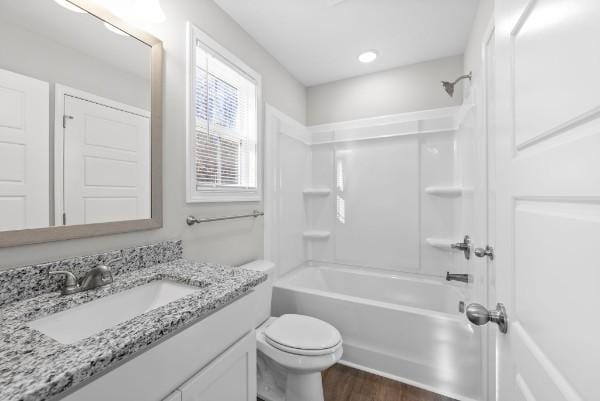 bathroom featuring  shower combination, toilet, wood finished floors, and vanity