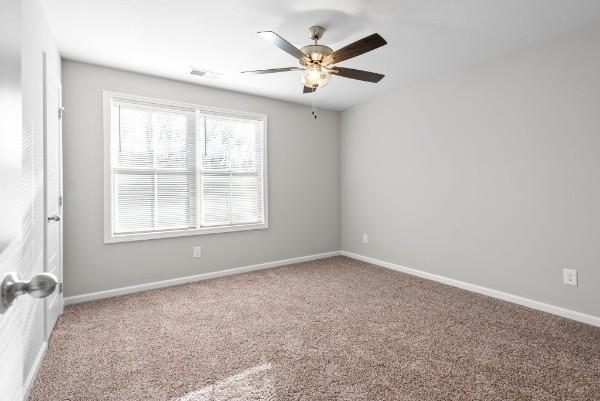 spare room featuring a ceiling fan, carpet flooring, and baseboards