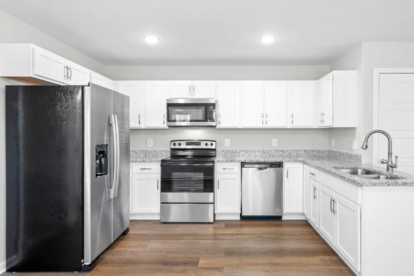 kitchen featuring white cabinets, dark wood-style floors, light stone counters, appliances with stainless steel finishes, and a sink