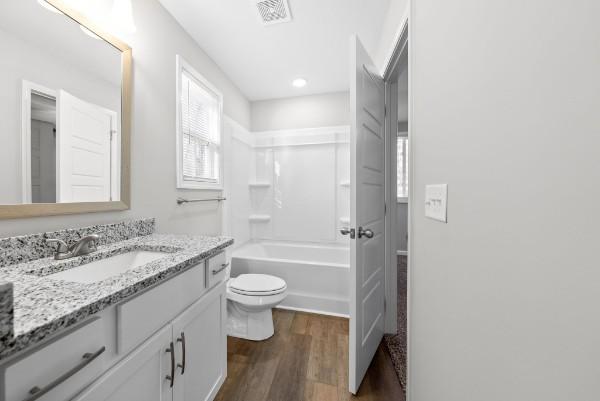 full bath with toilet, shower / bath combination, wood finished floors, vanity, and visible vents