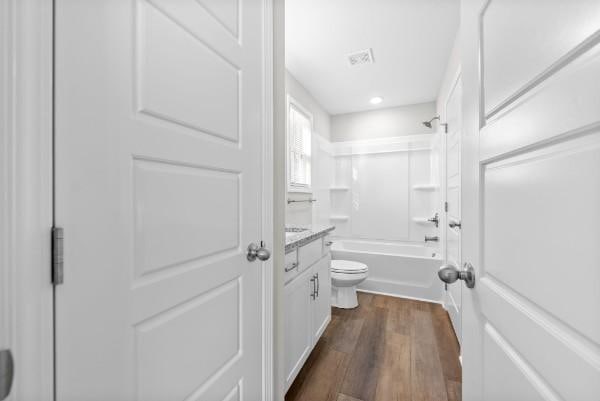 full bath featuring visible vents, shower / bathing tub combination, toilet, vanity, and wood finished floors