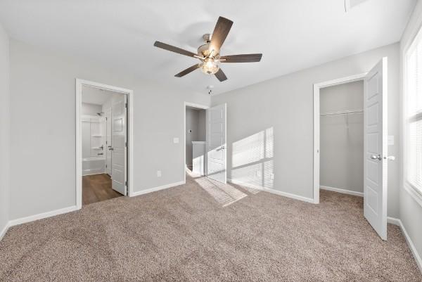 unfurnished bedroom with ceiling fan, carpet floors, a closet, and baseboards