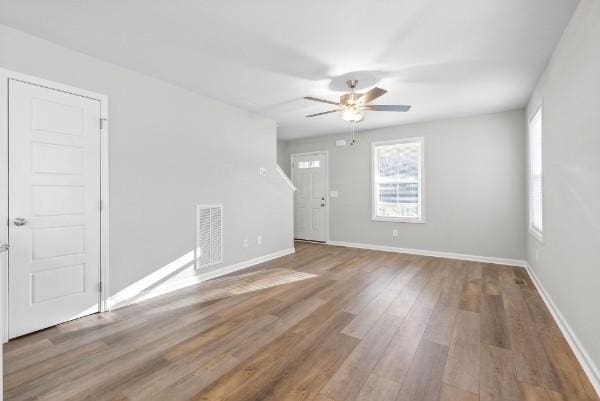 empty room with baseboards, visible vents, ceiling fan, and wood finished floors