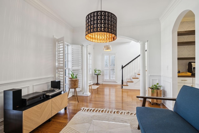 interior space featuring a decorative wall, wood finished floors, decorative columns, and crown molding