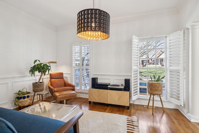 living area with decorative columns, crown molding, and a notable chandelier