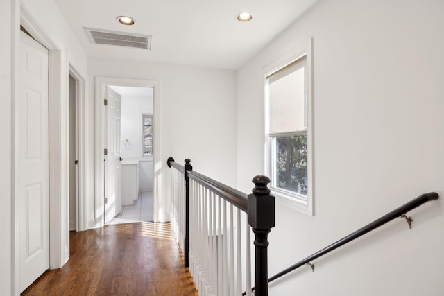 hall with dark wood-style floors, recessed lighting, visible vents, and an upstairs landing