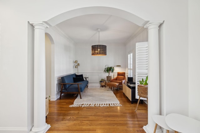 sitting room with decorative columns, ornamental molding, and wood finished floors