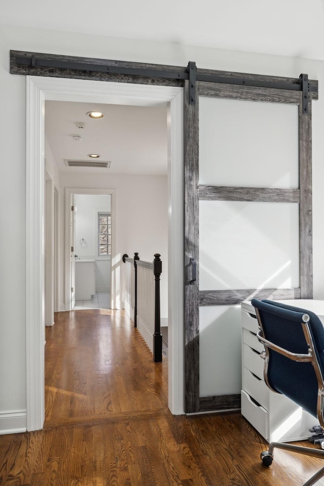 office area with dark wood-style floors, a barn door, and visible vents