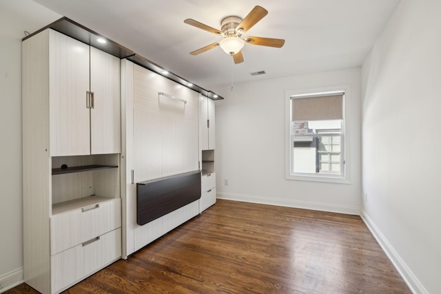 unfurnished bedroom with ceiling fan, dark wood-type flooring, visible vents, and baseboards