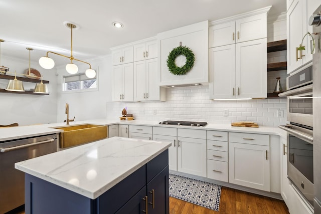 kitchen with appliances with stainless steel finishes, decorative light fixtures, light stone countertops, crown molding, and white cabinetry