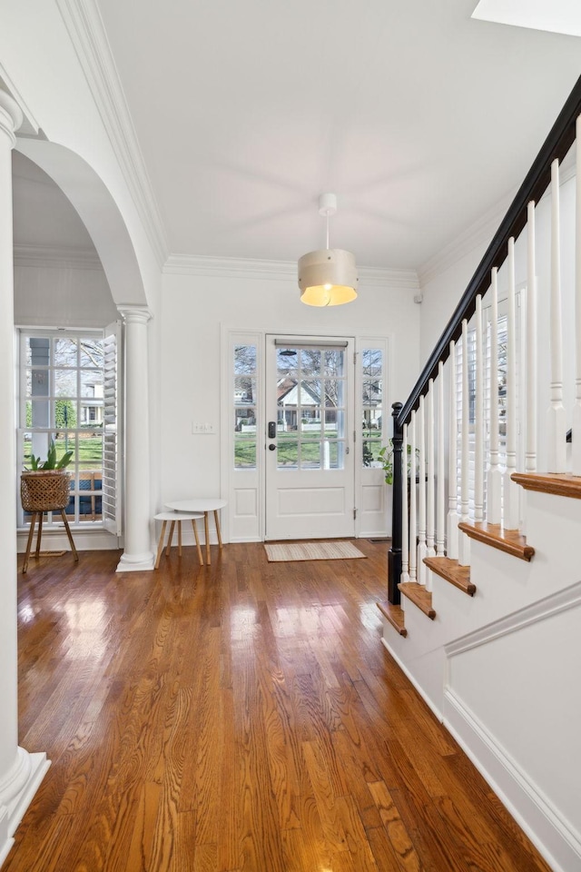 entrance foyer featuring decorative columns, stairway, and wood finished floors