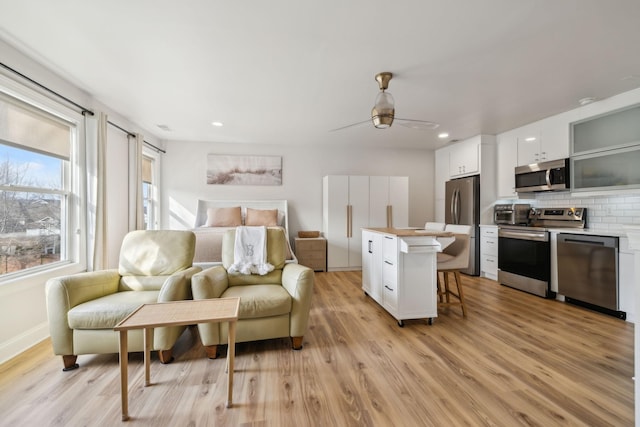 bedroom featuring recessed lighting, a ceiling fan, baseboards, light wood-style floors, and freestanding refrigerator