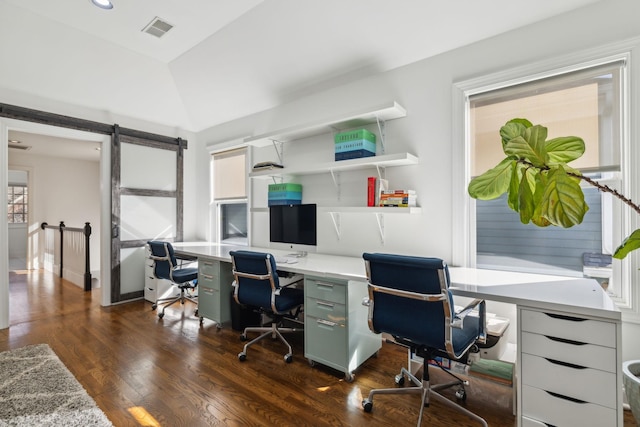 home office with dark wood-type flooring, lofted ceiling, visible vents, and a barn door