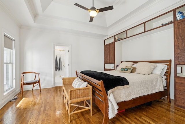 bedroom featuring ornamental molding, wood finished floors, a raised ceiling, and visible vents