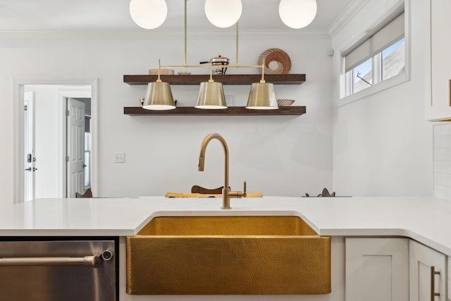 kitchen featuring ornamental molding, white cabinets, light countertops, and a sink