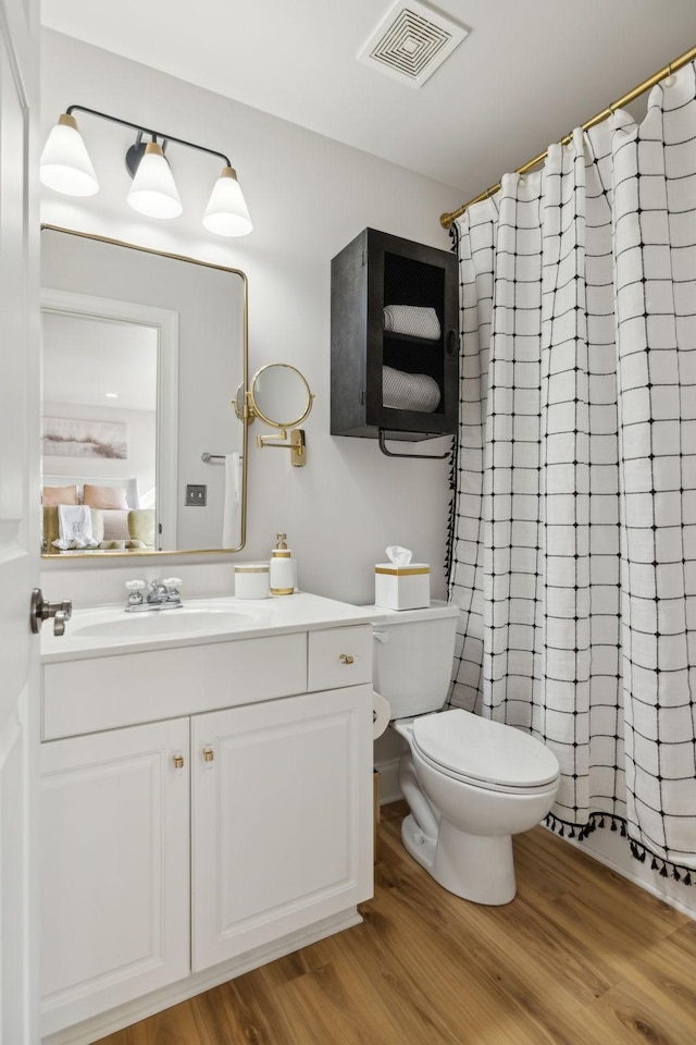 bathroom featuring visible vents, toilet, vanity, wood finished floors, and a shower with curtain