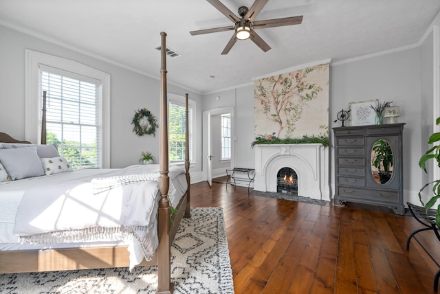 bedroom with a fireplace with flush hearth, ornamental molding, dark wood finished floors, and visible vents