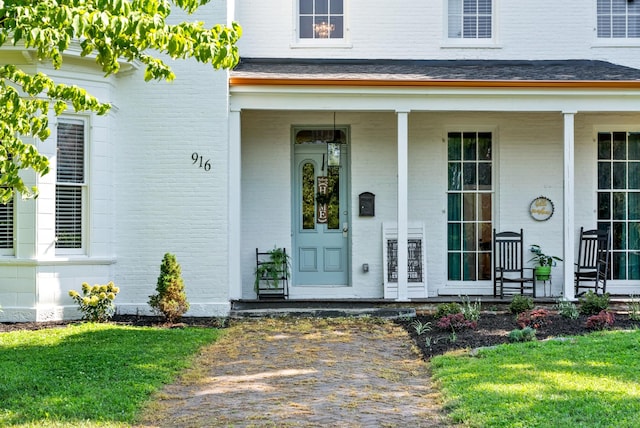 entrance to property with a lawn and brick siding