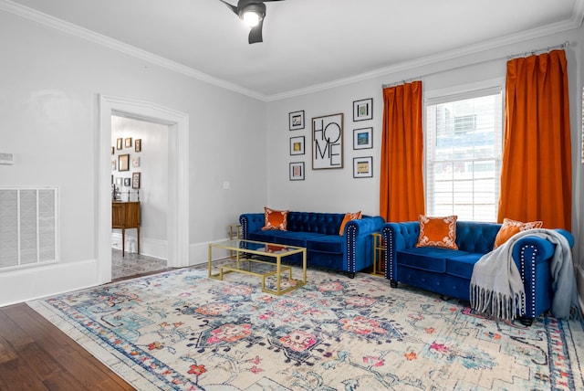 living room featuring baseboards, visible vents, a ceiling fan, ornamental molding, and wood finished floors